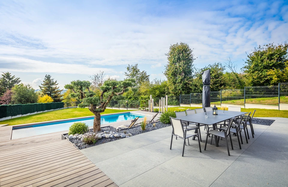 Espace extérieur résidentiel moderne avec terrasse aménagée comprenant salon de jardin, piscine rectangulaire et jardinage paysager