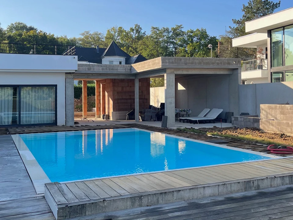 Piscine résidentielle extérieure avec spa intégré sous véranda grillagée