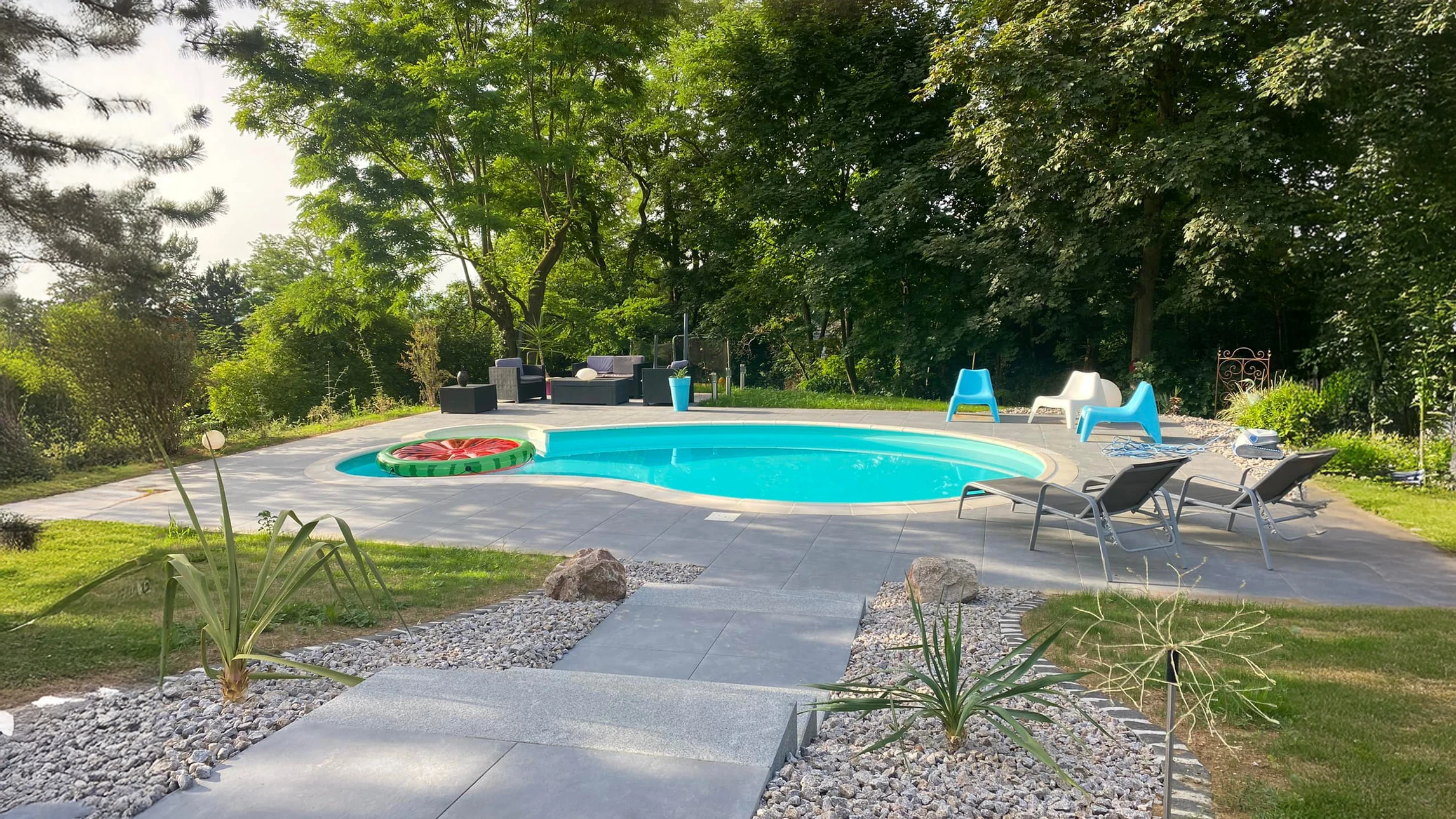 Piscine extérieure avec eau cristalline bleu turquoise, échelle métallique chromée intégrée au rebord