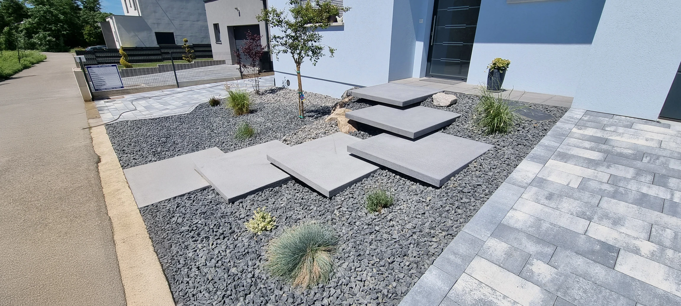 Jardin paysager avec pelouse verdoyante, arbustes taillés et buissons fleuris roses