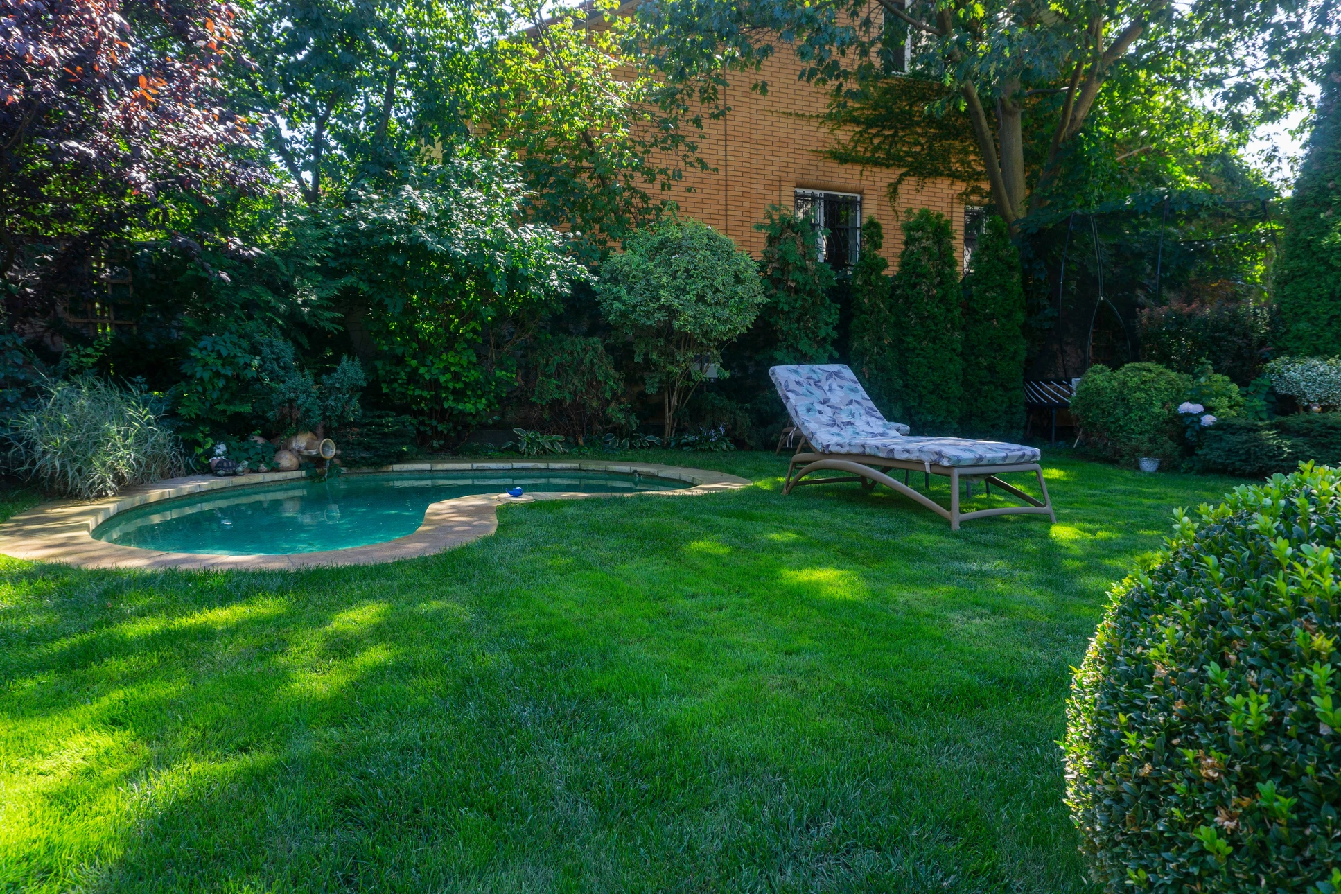 Scène extérieure de jardinage professionnel avec homme utilisant une tondeuse autoportée orange sur pelouse verte entretenue